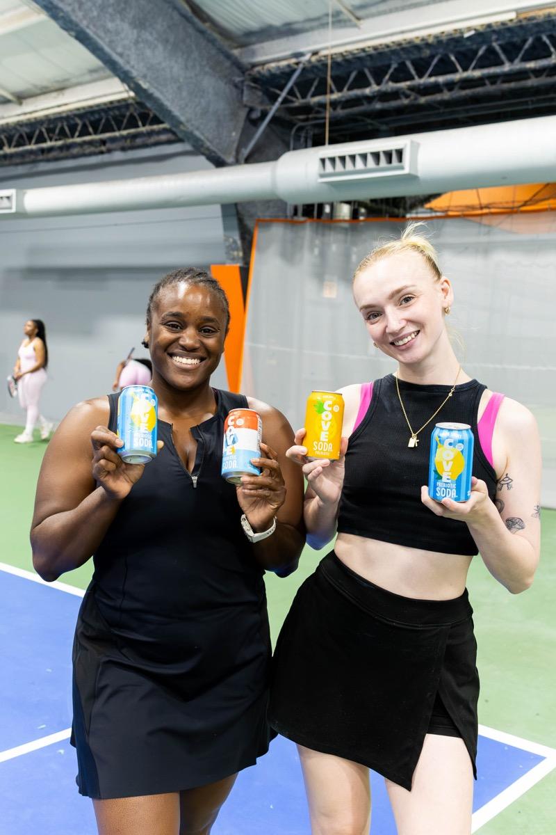 Body by MJ members holding Cove Soda cans at an event