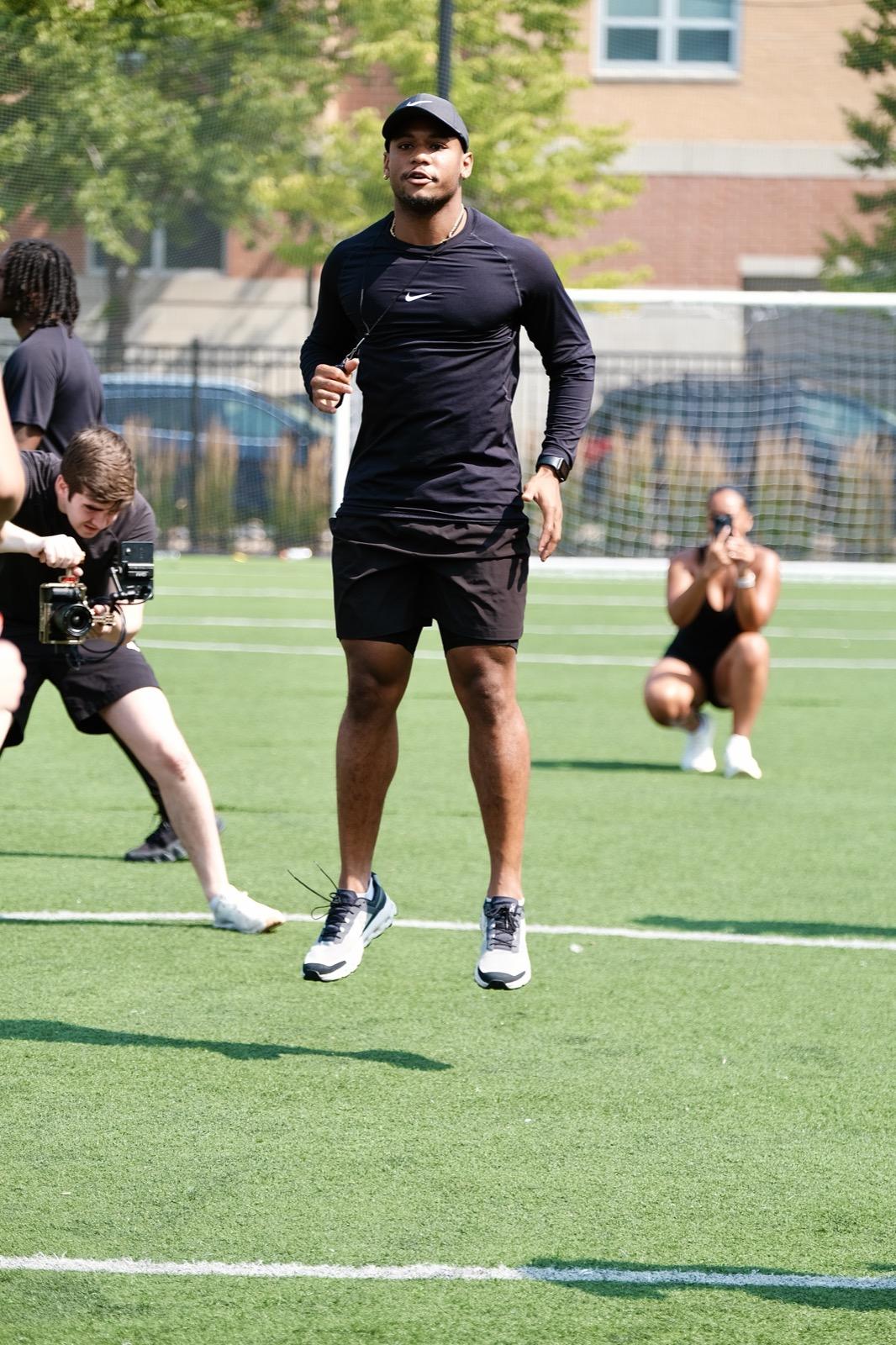 Marcus Jones jumping with energy while coaching a Body by MJ field class